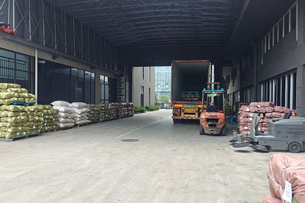 A forklift loads pallets into a container